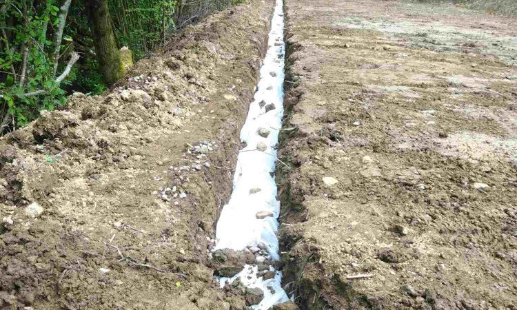 Fermeture du géotextile avant remblaiement de la tranchée pour terminer les travaux de drainage à Saint Mury Monteymond 38190